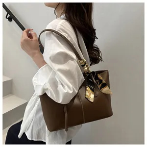 Detail of dark brown leather tote bag featuring contrast stitching and a printed silk scarf