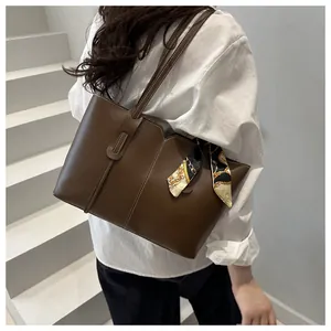 Detail of coffee brown tote bag with matte leather finish and decorative silk scarf