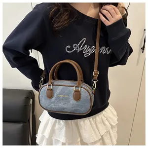 Detailed view of denim bowling bag with leather handles and gold fashion lettering