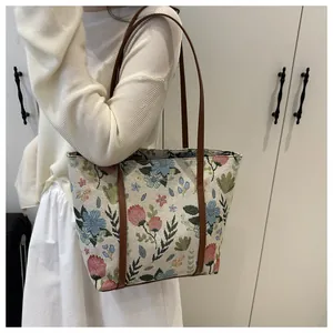 Detail of floral tapestry tote bag with brown leather straps shown on a model