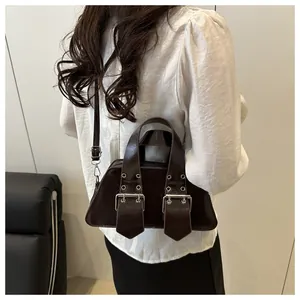 Detail of dark brown retro punk shoulder bag with silver eyelets and buckles on model