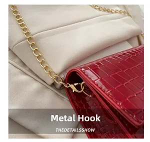 Detail van rode tas met krokodillenprint, luxe gouden metalen ketting en hardware sluiting