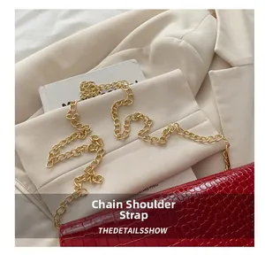 Detailoverzicht van de gouden metalen ketting op een rode crossbodytas met krokostructuur