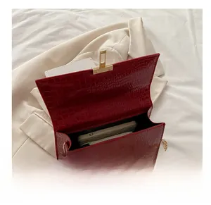 Detail van rode tas met krokodillenprint, goudkleurig slot en ruimte voor mobiel
