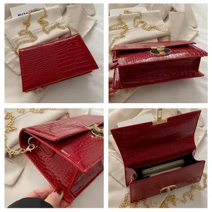 Details van rode tas met krokodillenpatroon, gouden ketting en metalen sluiting