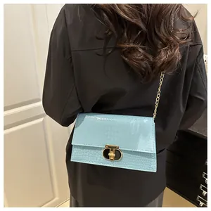 Detail van de lichtblauwe crossbodytas met krokodillenreliëf en gouden kettingband
