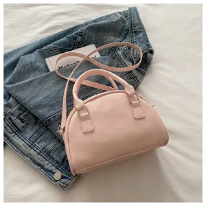 Détail d'un sac à main demi-lune rose clair avec ferrures argentées et bandoulière