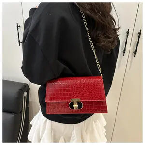 Detail van rode tas met krokodillenprint, gouden ketting en metalen draaisluiting