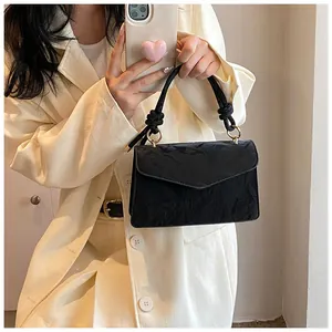Close-up of black crossbody bag with pleated texture and thick knotted handle detail