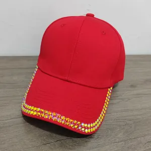 Detail of red cotton baseball cap featuring iridescent rhinestones on the brim edge
