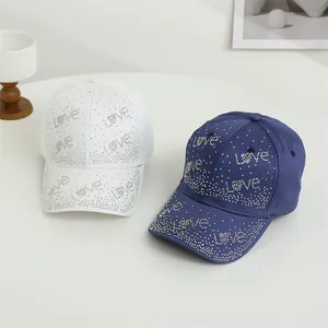 Vue détaillée du lettrage LOVE en strass brillants sur casquettes blanc et marine
