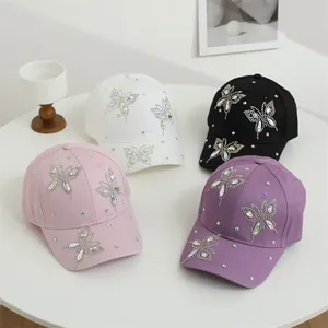 Dettagli di quattro cappellini da baseball con farfalle di strass colorati in rosa e nero