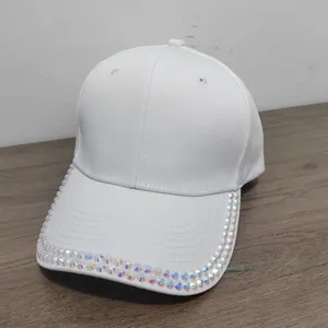 Detail of white cotton baseball cap showing dual rows of iridescent rhinestones on the brim