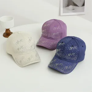 Détail du lettrage Love en strass étincelant sur casquettes de baseball blanc et marine
