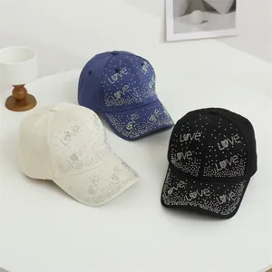 Gros plan des motifs Love en strass étincelants sur trois casquettes en coton colorées