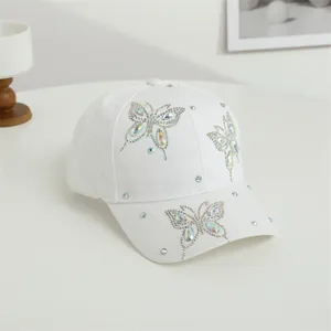 Dettaglio del cappellino bianco con decorazioni di farfalle in strass luccicanti