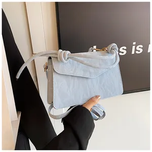 Close-up of light blue PU leather handbag showing marble texture and knotted strap detail