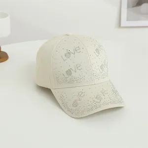 Vue détaillée d'une casquette en coton crème avec motif Love en strass multicolores