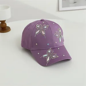 Dettaglio di farfalle in strass scintillanti su un berretto da baseball in cotone viola