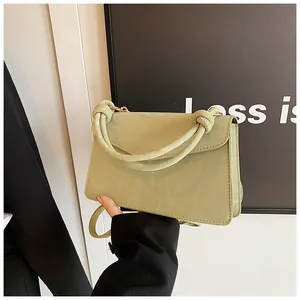 Detailed view of pistachio green handbag featuring a twisted handle and textured leather