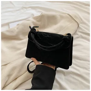 Detail of black velvet crossbody bag with unique knotted handle and gold hardware