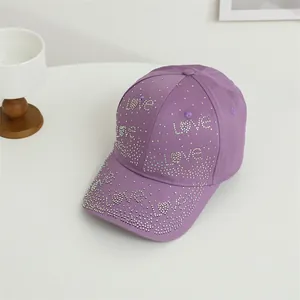 Détail de strass argentés formant le mot love sur une casquette en coton violette