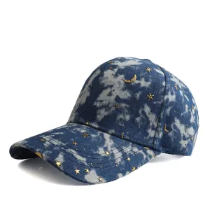 Detailed close-up of blue denim baseball cap with gold star and moon embroidery