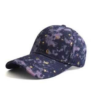 Macro view of blue tie-dye baseball cap featuring gold star and moon patterns