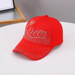 Dettaglio del cappellino rosso con scritte Queen in strass scintillanti e design a corona