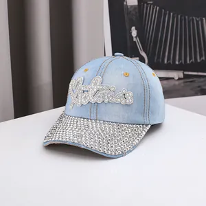 Dettaglio degli strass luccicanti sul berretto in denim azzurro con motivo a lettere