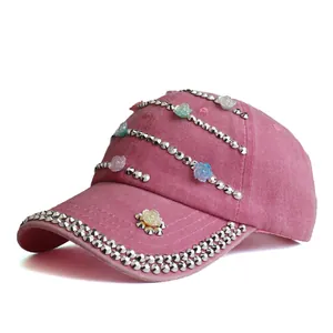 Detail of pink washed cotton baseball cap with silver metal rivets and resin roses