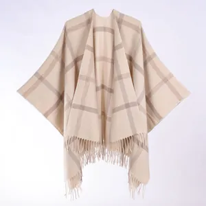 Detailed view of beige and brown checkered poncho with fringe trim and soft knit texture