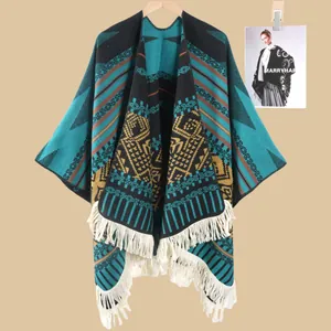 Detail eines Ethno-Strickponchos mit geometrischem Jacquardmuster und weißen Fransen