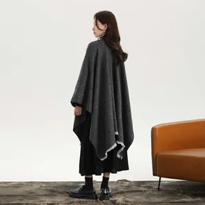 Detail of dark gray knit shawl with fringe trim on model in elegant studio setting