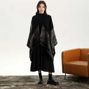 Détail d'un poncho tricoté noir pour femme avec un motif de paysage de forêt grise