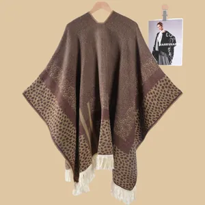 Detail eines Boho-Strickschals mit Leopardenmuster und langen weißen Fransenbesätzen
