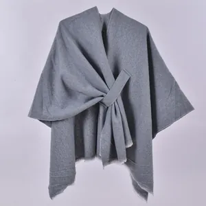 Detail of grey knitted shawl cape featuring side-tie design and textured fabric