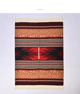 Close-up of geometric tribal pattern and cream fringe on a red knit poncho wrap