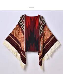 Detail of ethnic geometric knit poncho with red and black diamond patterns and tassels