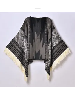 Detail of geometric tribal knit pattern and white tassel fringe on the poncho cape
