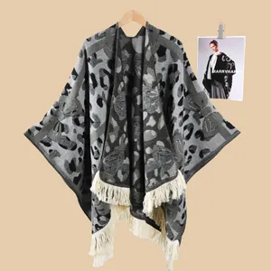 Detail eines grau-schwarzen Strickschals mit Tiermuster und langen cremefarbenen Fransen