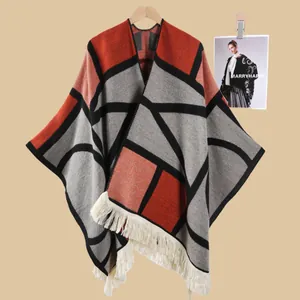 Detail eines rot-grauen geometrischen Strick-Ponchos mit cremefarbenen Fransen