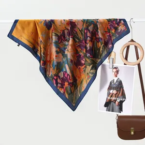 Detail van elegante mosterdzijden vierkante sjaal met artistieke bloemenprints en randen