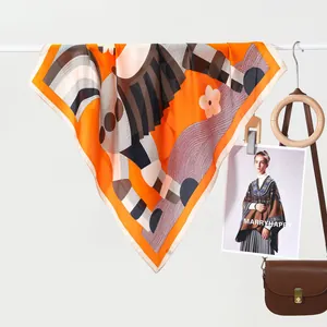 Detailweergave van een oranje zijden vierkante sjaal met geometrische bloemmotieven