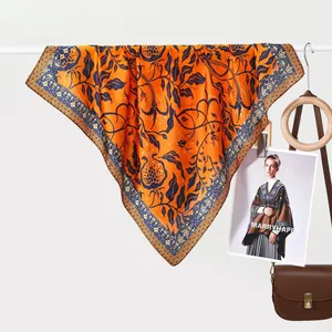 Classic orange silk-feel floral scarf with navy botanical patterns hung for display