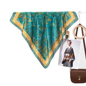 Classic floral silk scarf in turquoise and gold hanging naturally on a white rod
