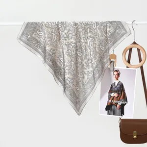 Detail of vintage paisley silk scarf elegantly draped with luxury leather handbag