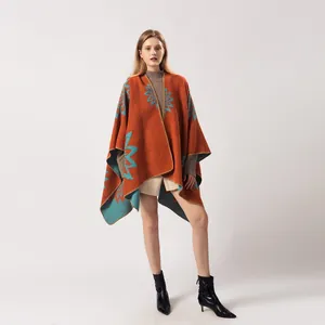 Détail d'un poncho en maille à fleurs avec motifs bleus sur une base orange vive et élégante