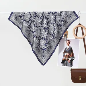 Navy blue paisley silk scarf with white floral patterns hanging on a rack