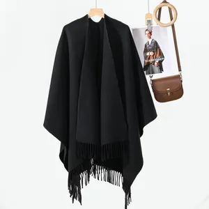 Dettaglio di uno scialle nero a maglia con lunghe frange su un appendiabiti in legno